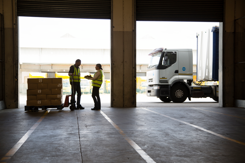 Workers moving stock and loading a lorry in a food distribution warehouse